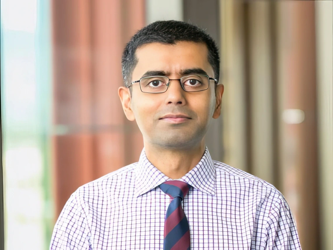 A man in a patterned tie smiles at the camera.