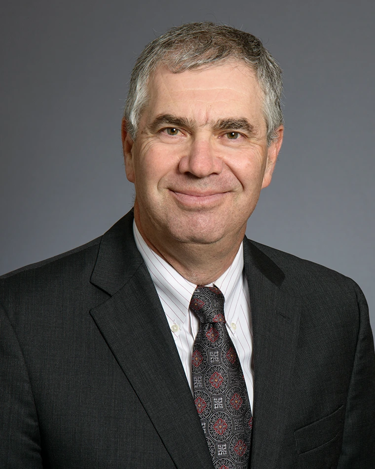 person wearing dark business suit, white shirt and tie